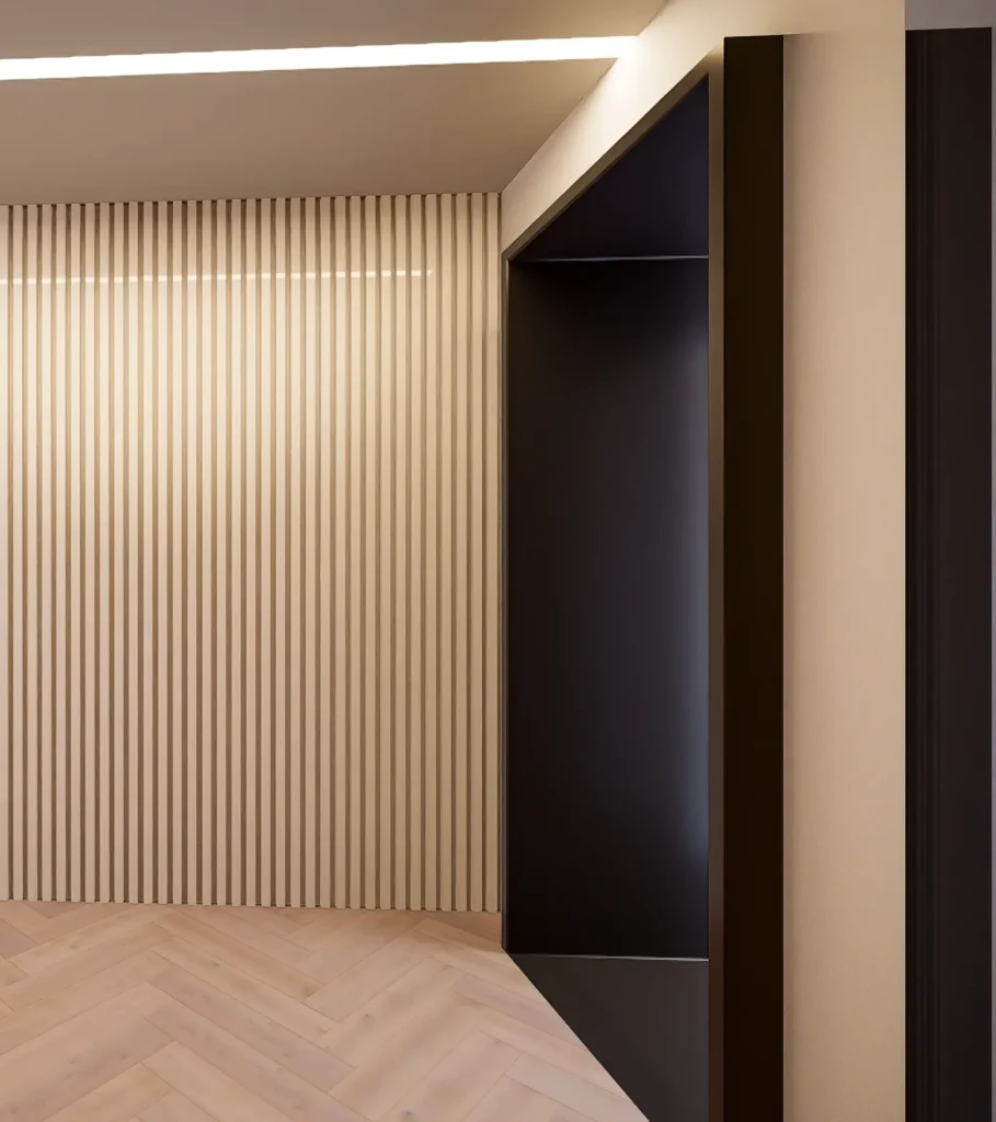 Detail interiéru s vertikálnou lamelovou stenou v béžovom odtieni, kontrastujúcim tmavým architektonickým portálom a drevenou podlahou.